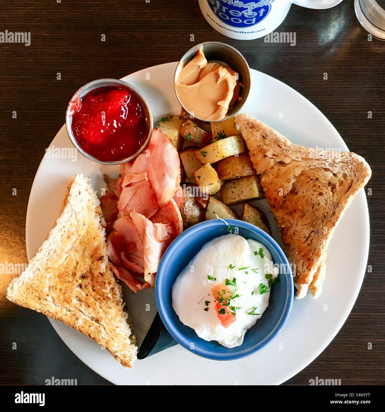 Full North American breakfast of poached egg, ham, fried potatoes, and toast with peanut butter and jam. - Smartphone Captured Stock Image