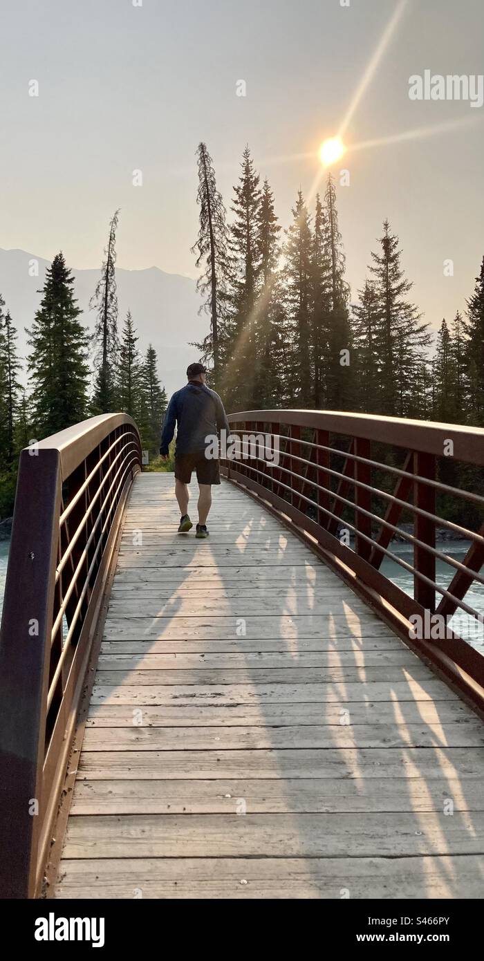 A man crosses a foot bridge over the Kootenay River in Kootenay National Park, Alberta, Canada. - Smartphone Captured Stock Image