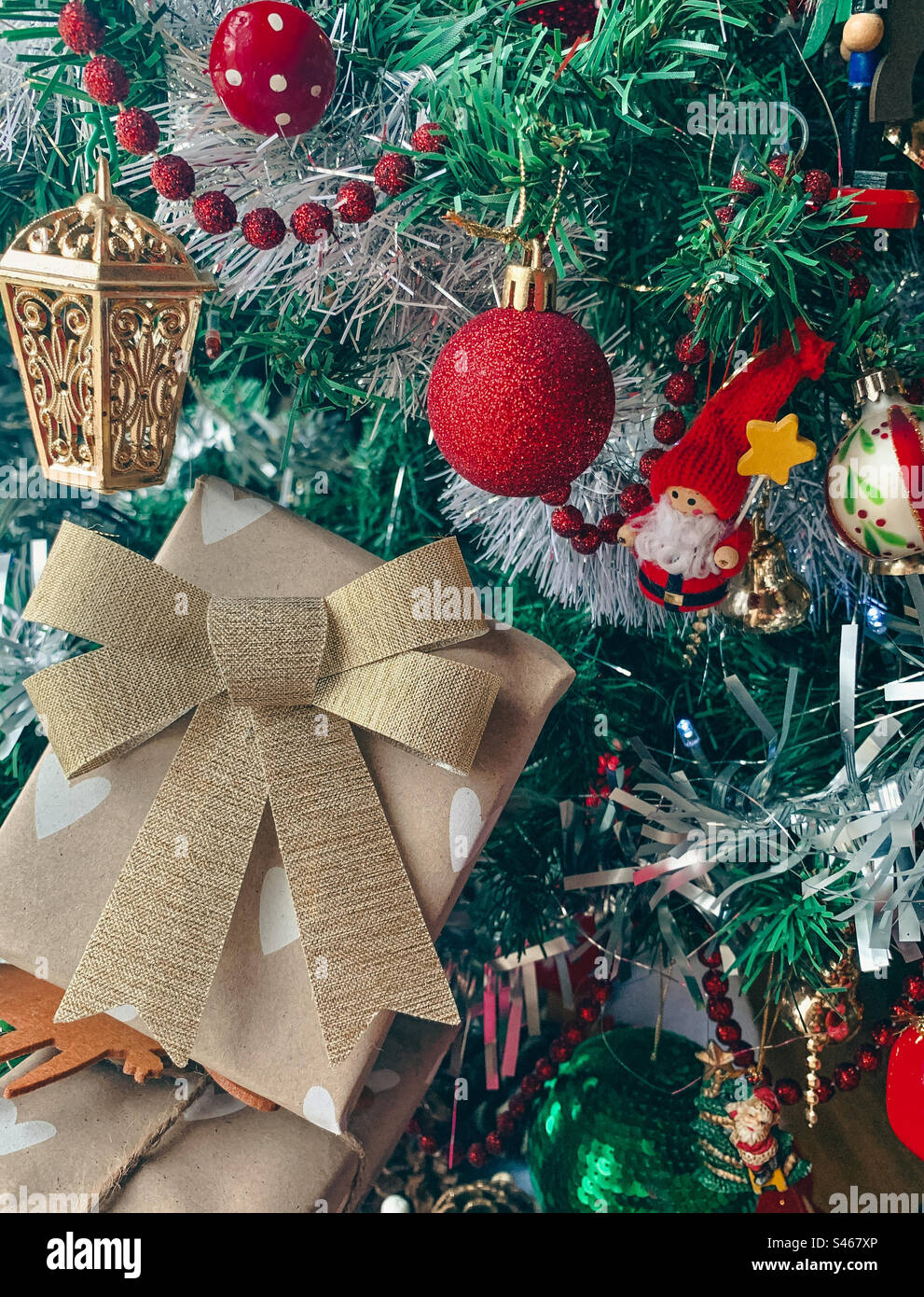 Present with a bow on a Christmas tree with ornaments - Smartphone Captured Stock Image