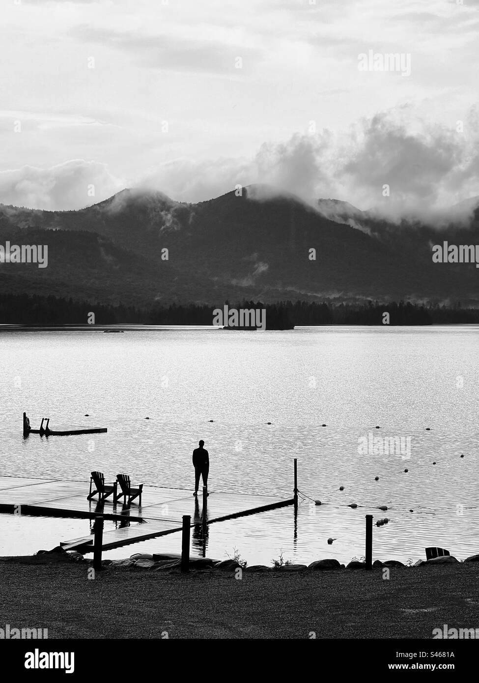 A solitary man standing on a dock at the edge of Elk Lake with the