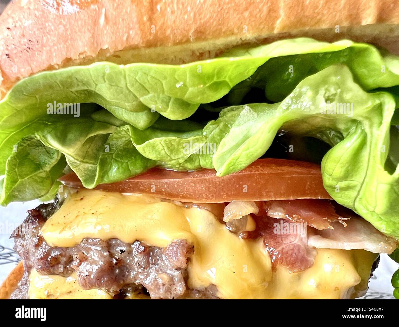 Burger in a bun with melted cheese, bacon and tomato Stock Photo