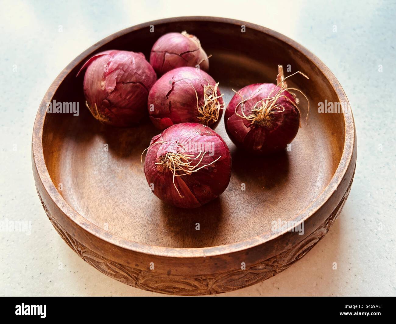 Five red onions in a circular wooden bowl. Overhead shot. Still life. Fresh, colourful, juicy,nutritious, popular, vegetable, that will make you cry when you chop it up. - Smartphone Captured Stock Image