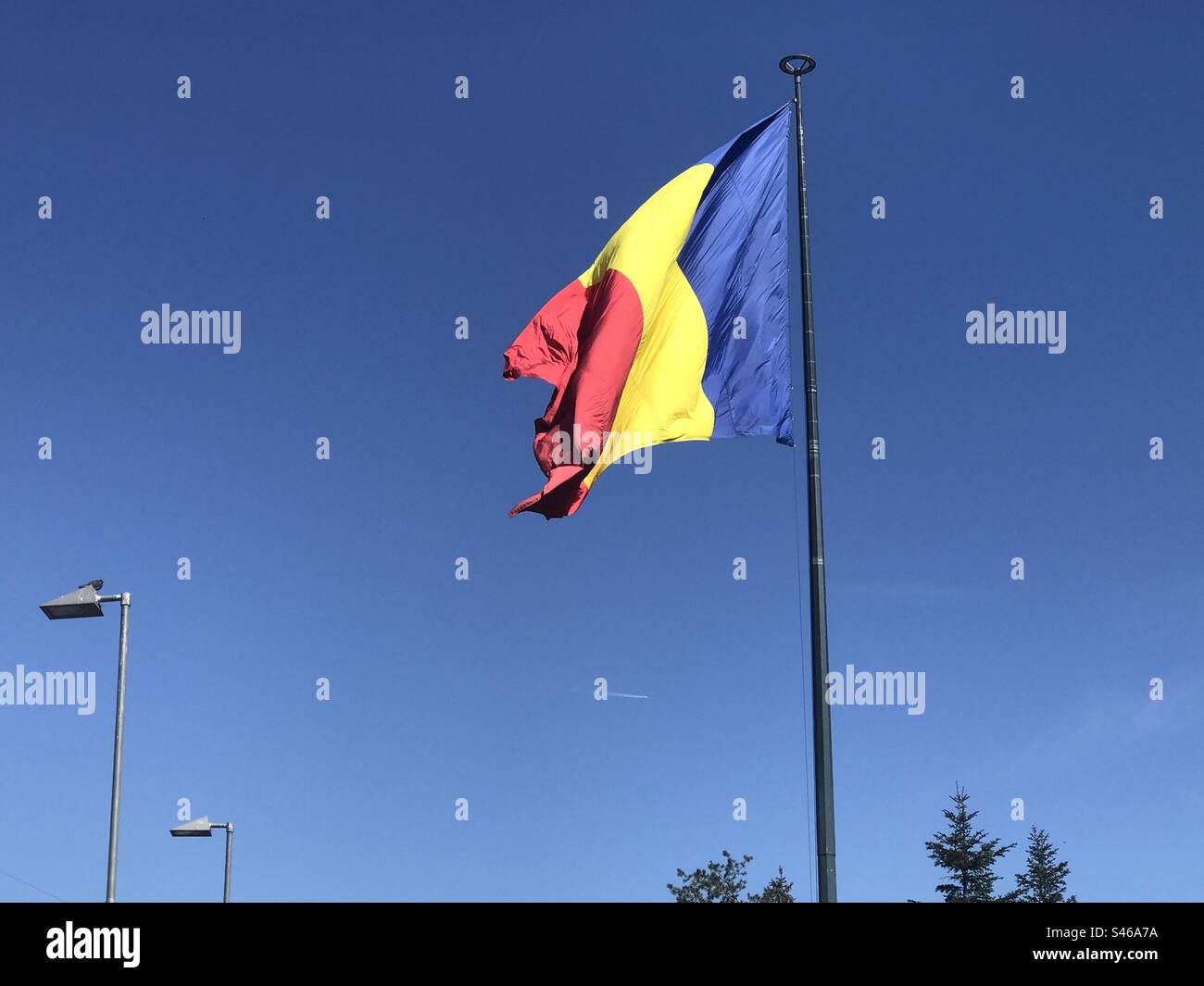 The Romanian flag flies high on a bright and sunny day. Stock Photo