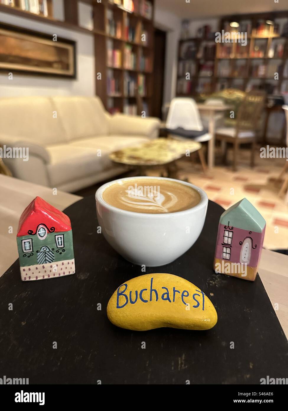 Colorful relaxing moments in a bar of Bucharest with handmade painted miniature houses and a yellow colored stone - Smartphone Captured Stock Image