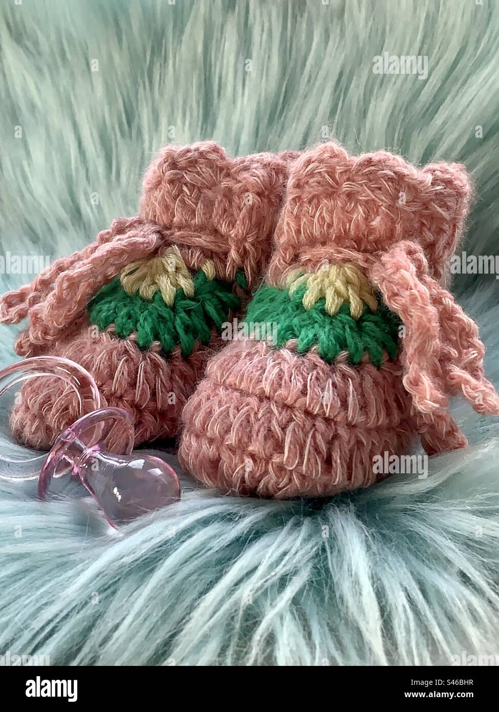 Pink knitted baby booties on a background of blue faux fur - Smartphone Captured Stock Image