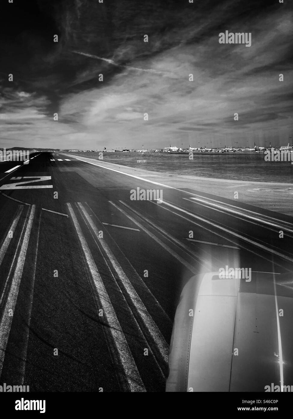 Close view of Rolls-Royce jet engine when airplane it’s about to tack off,with track line and surrounding landscape as background, in chromatic tone. - Smartphone Captured Stock Image