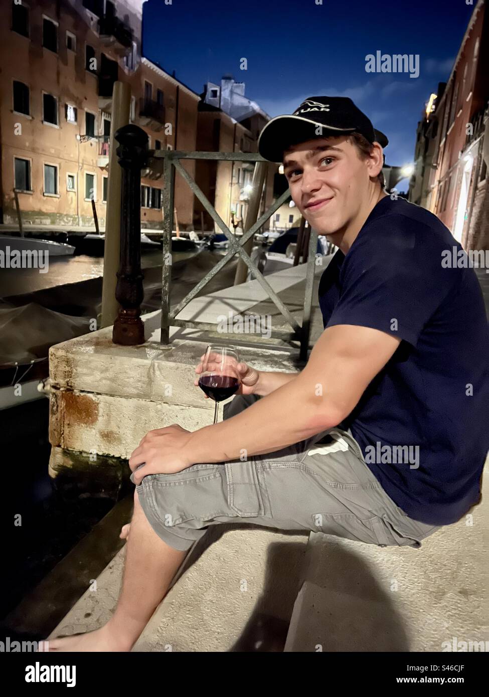 Young adult enjoying an evening glass of wine on a canal in Venice - Smartphone Captured Stock Image