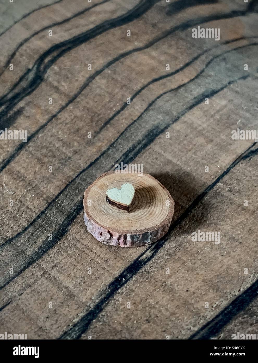 A small wooden heart on assorted wooden backgrounds - Smartphone Captured Stock Image