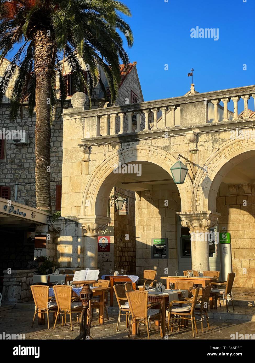 OTP bank on Hvar waterfront, Croatia, with cafe chairs and tables outside. - Smartphone Captured Stock Image