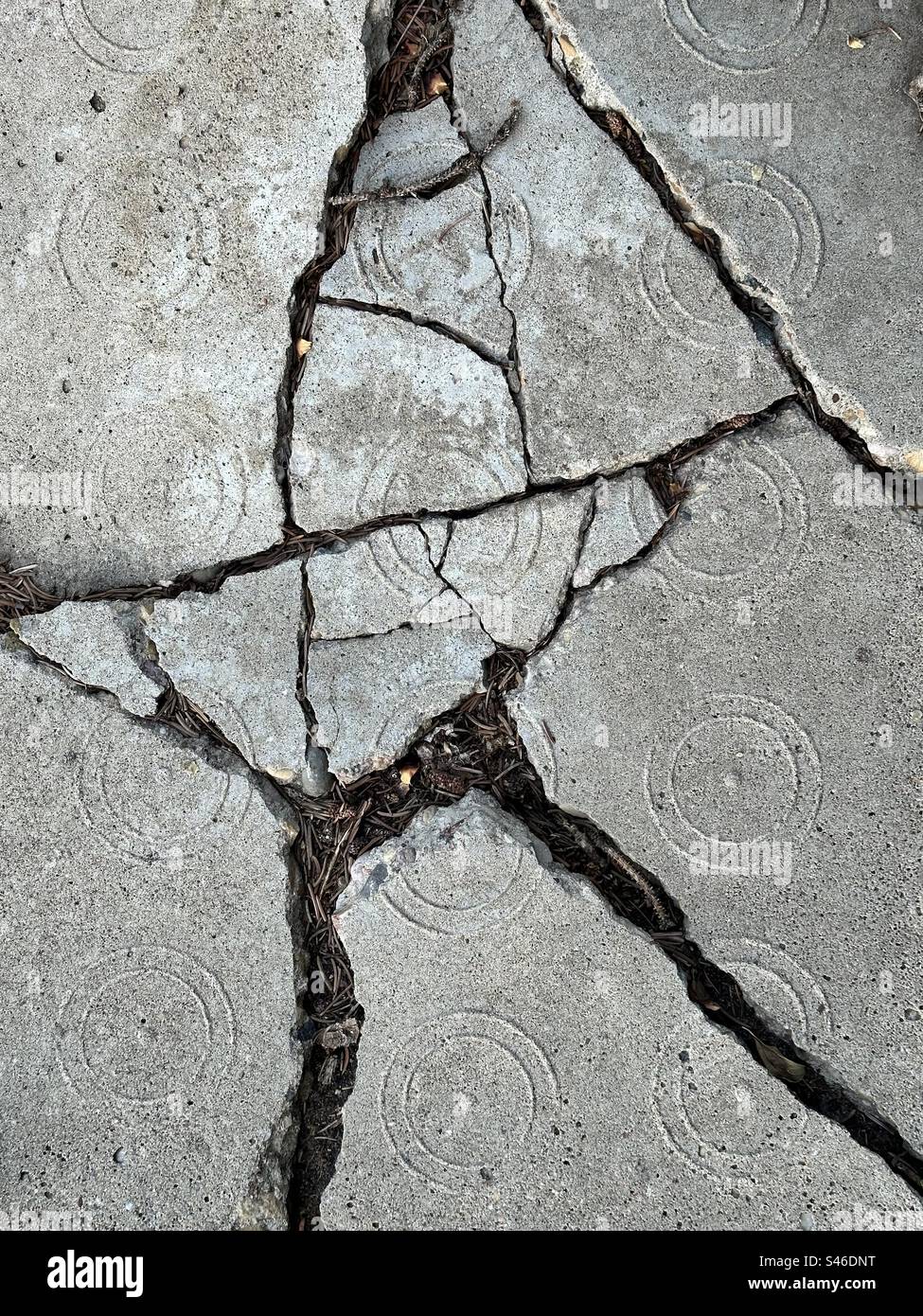Cracked sidewalk block with circular pattern - Smartphone Captured Stock Image