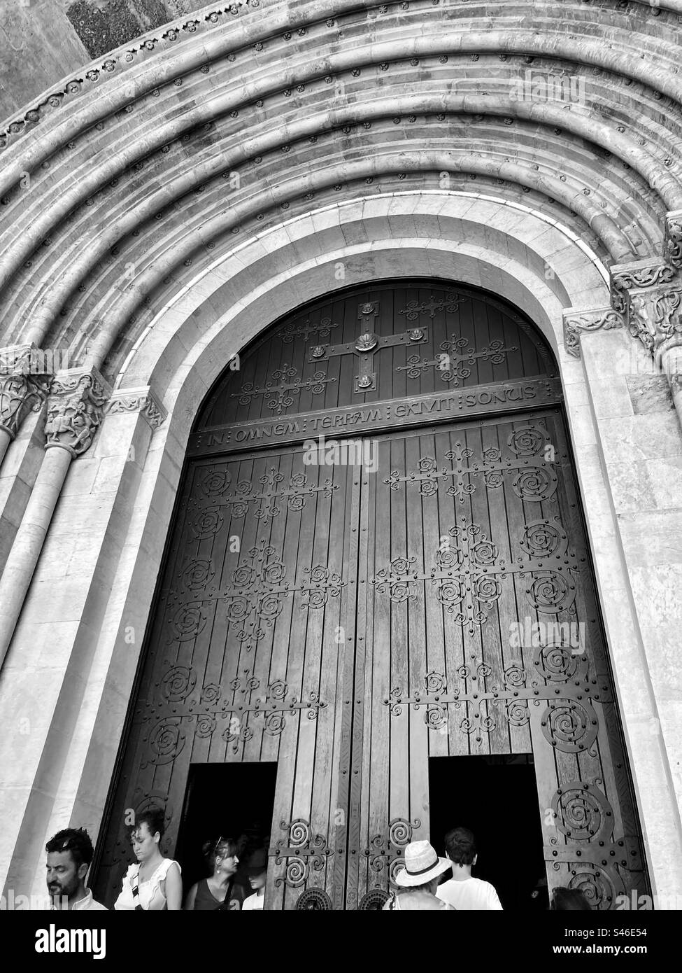 Arch and door of Se Cathedral in Lisbon( cathedral of Saint Mary Major ( Santa Maria Maior)  and tourists in monochromatic tone. Stock Photo