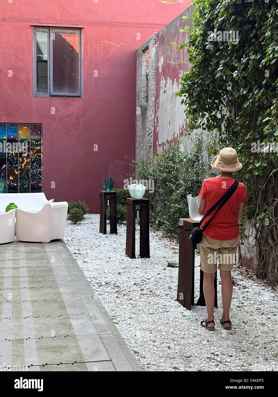 Back view of woman looking at a Venician glass bowl in an outdoor gallery space Stock Photo