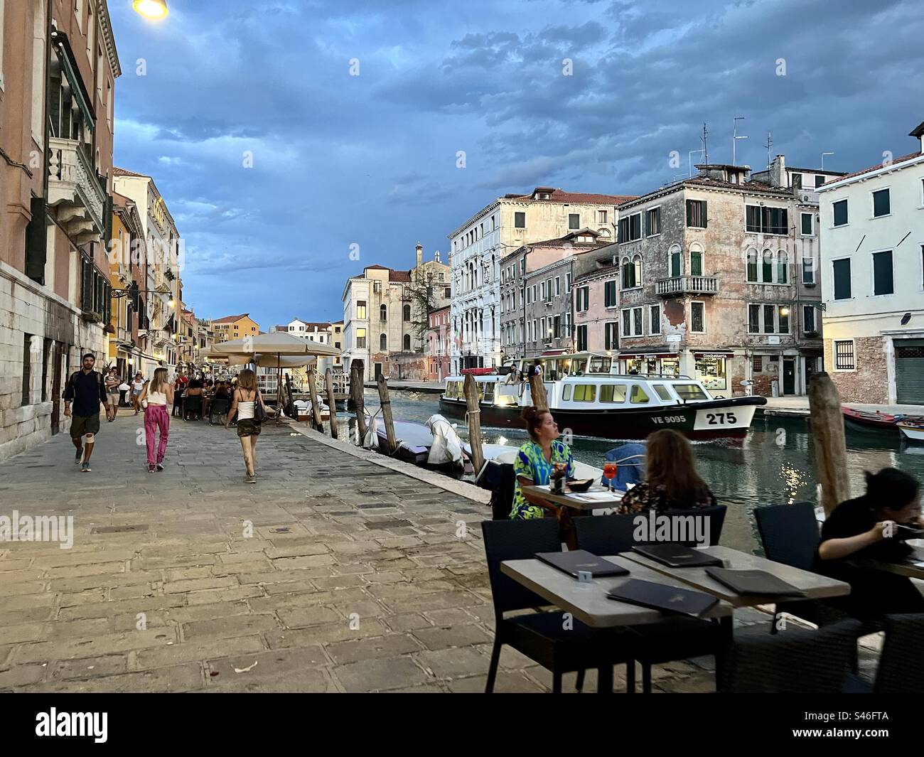 People enjoying food and evening walks on a summer night  by Canale di Cannaregio, Venice - Smartphone Captured Stock Image