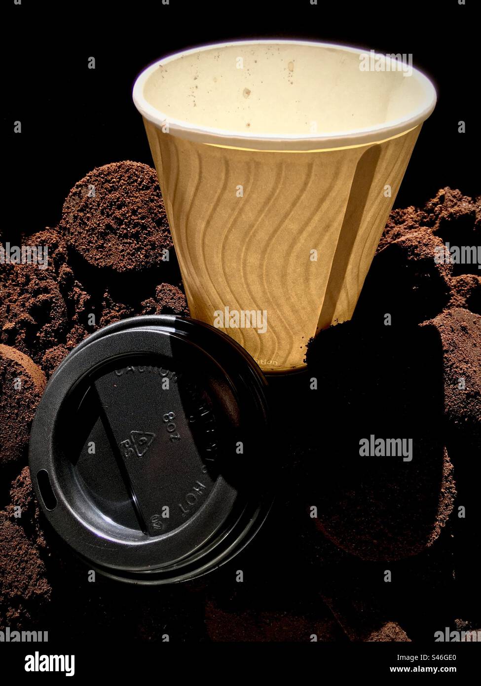 Warm coffee cup with plastic lid on bed of coffee grounds - Smartphone Captured Stock Image