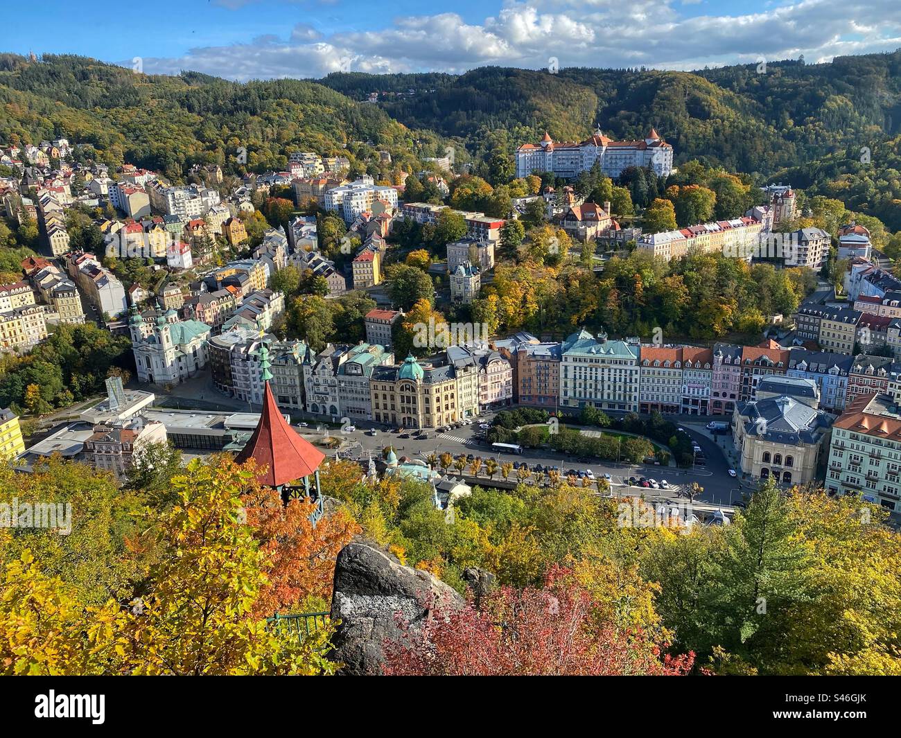 High-angle view at Karlovy Vary surrounded by autumn colored forests and hills, Czech Republic. - Smartphone Captured Stock Image