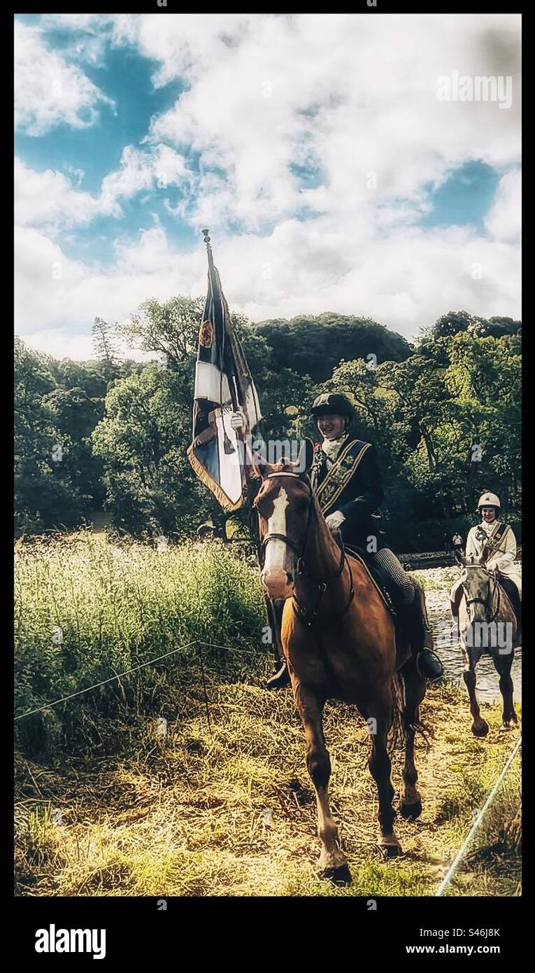 Horse rider carrying a flag crossing a river. Stock Photo