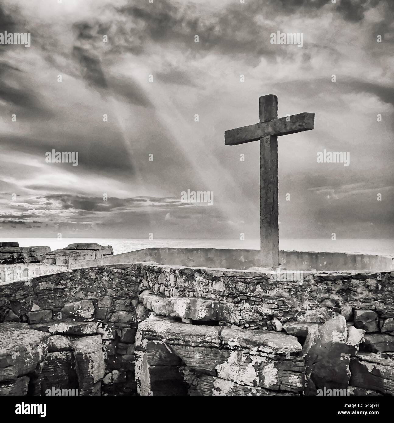 Stone cross caught in beams of sunlight on the coast of Peniche, Portugal - Smartphone Captured Stock Image