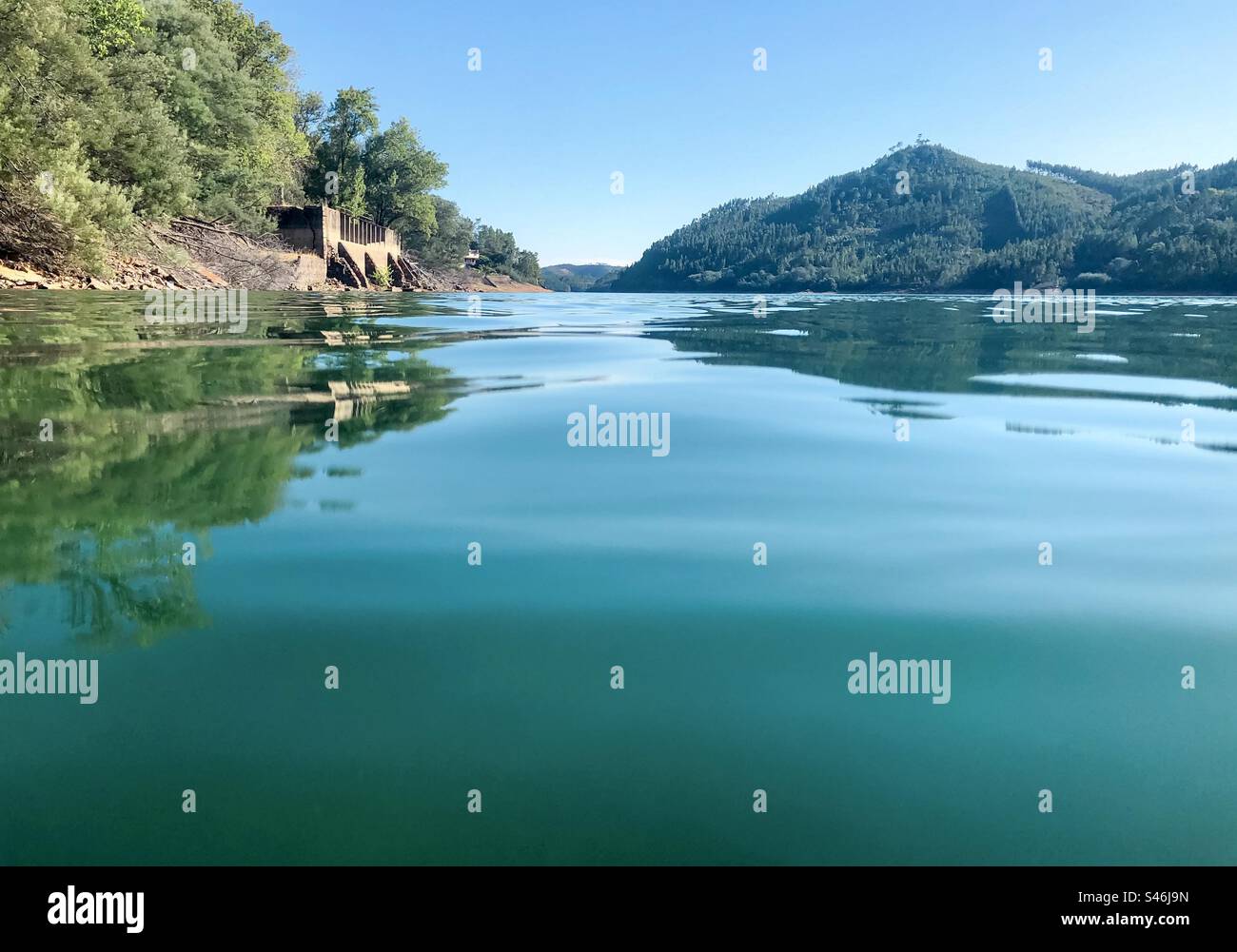 In the Zêzere river, looking across blue water to land beyond - Smartphone Captured Stock Image