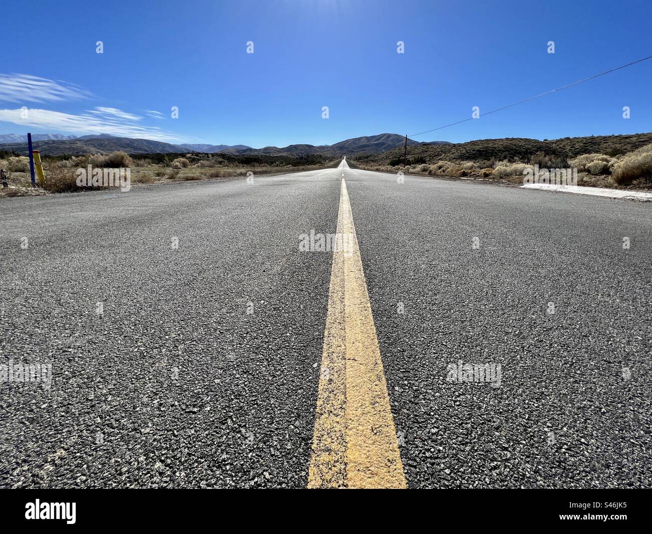 View along road leading to mountains in southern California, taken with camera low to ground. Blue sky overhead - Smartphone Captured Stock Image