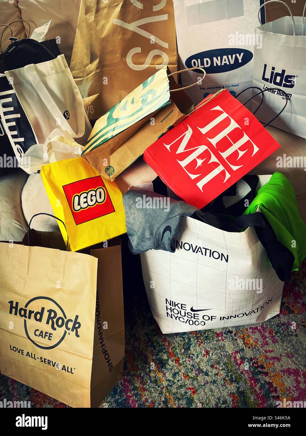 Shopping bags from a shopaholic spending spree stacked on apartment sofa in Midtown Manhattan, 2023, New York City, USA Stock Photo