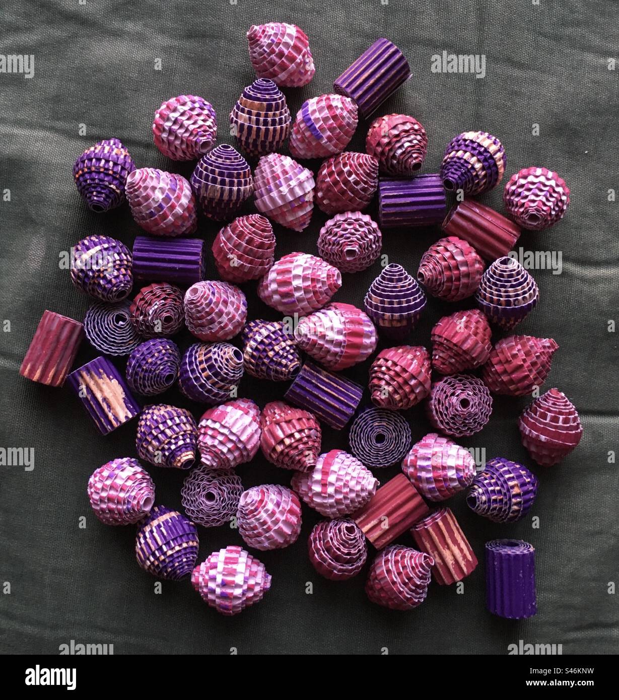Perle di carta colorate  fatte a mano su un tavolo verde. Colored hand made paper beads on a green table. Rosa, lilla, viola. Pink, lilac, violet - Smartphone Captured Stock Image
