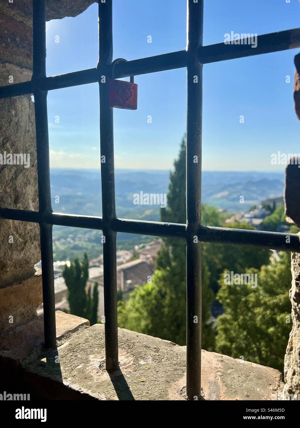 Looking out on San Marino through a grated window with one padlock in Guaita Tower - Smartphone Captured Stock Image