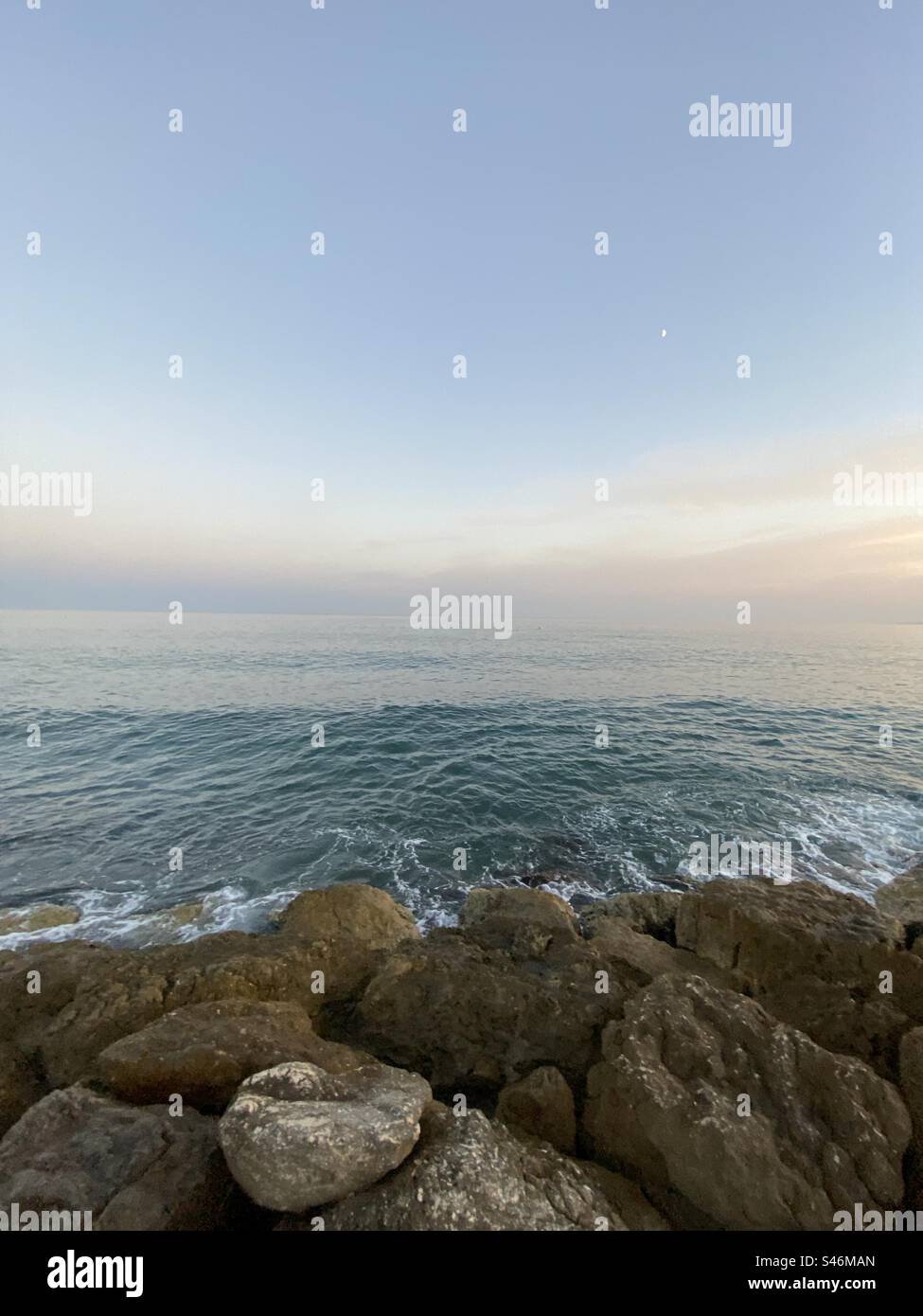 A photo of the shore of a rocky beach during a sunset. - Smartphone Captured Stock Image