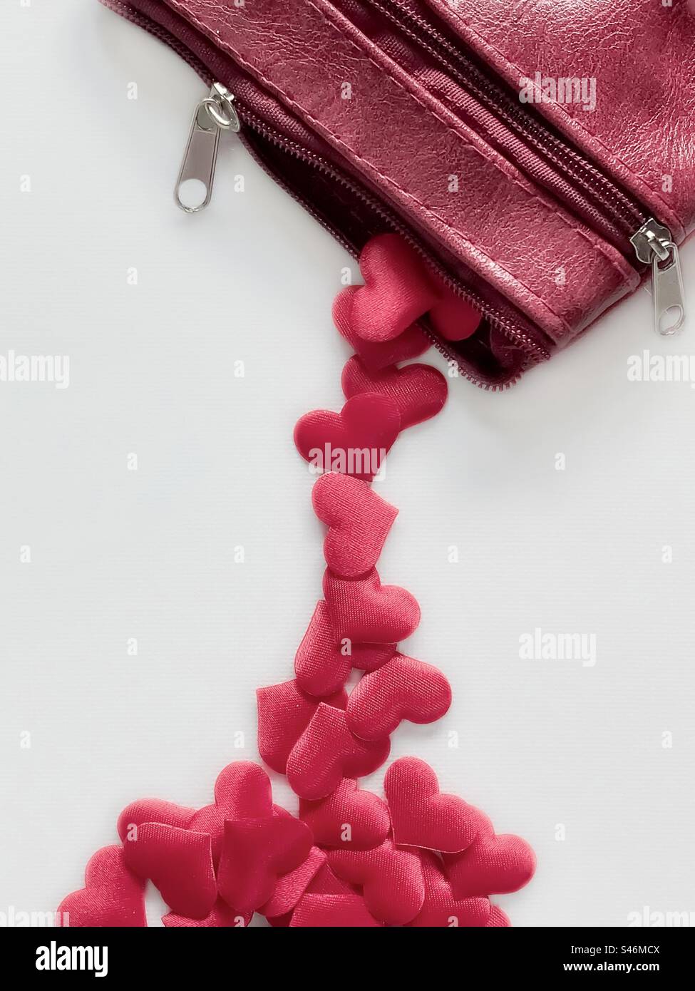 Red purse pours out heart shapes on white background - Smartphone Captured Stock Image
