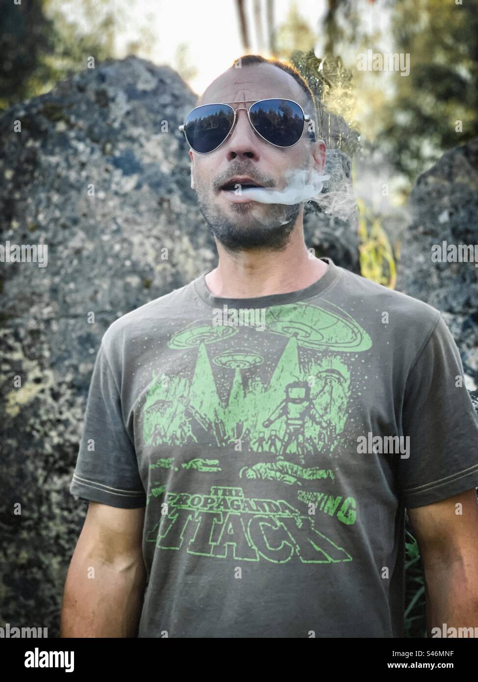 Man in sci-fi T-shirt and shades exhaling smoke Stock Photo