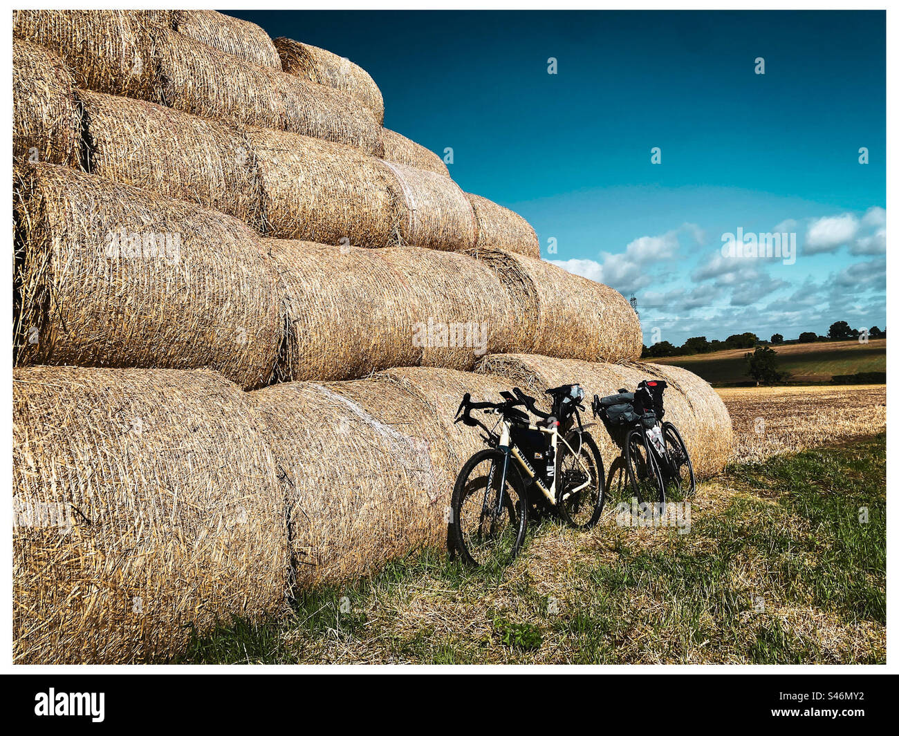 Two bikepacking bikes lean against a hay stack in Norfolk England - Smartphone Captured Stock Image