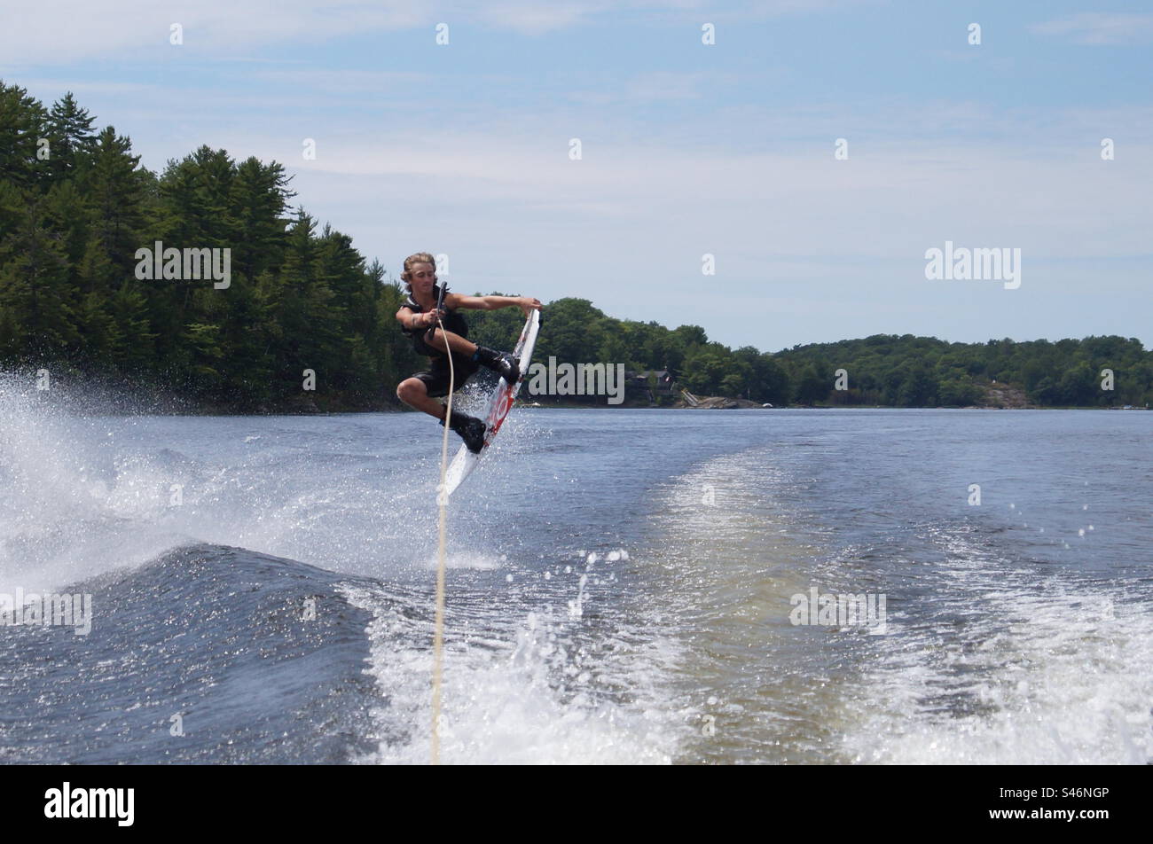 Wakeboarding in cottage country, jumping across the water Stock Photo