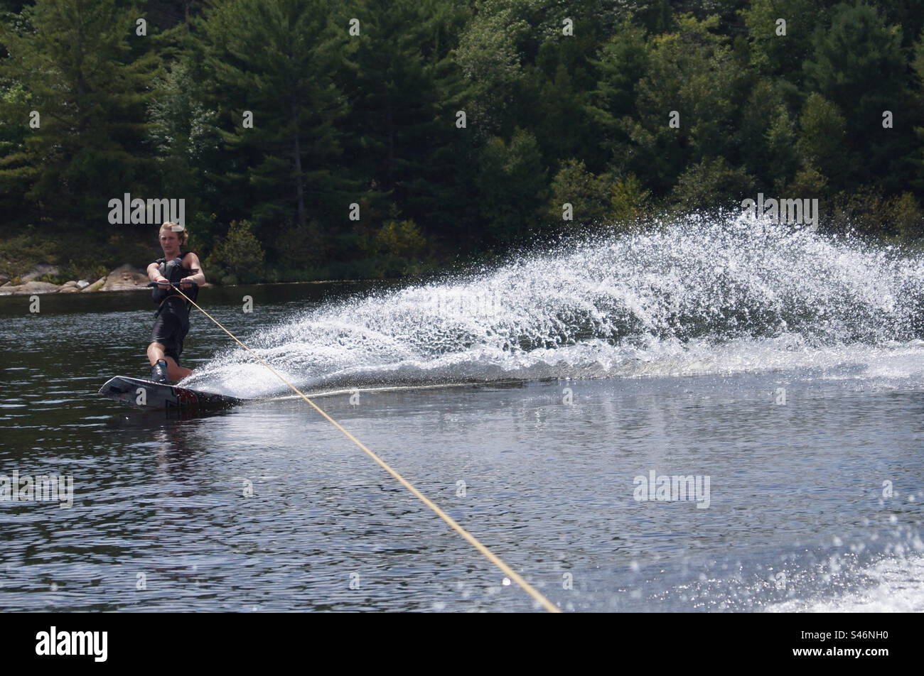 Water flying as wakeboarder cuts hard across a lake in Parry Sound