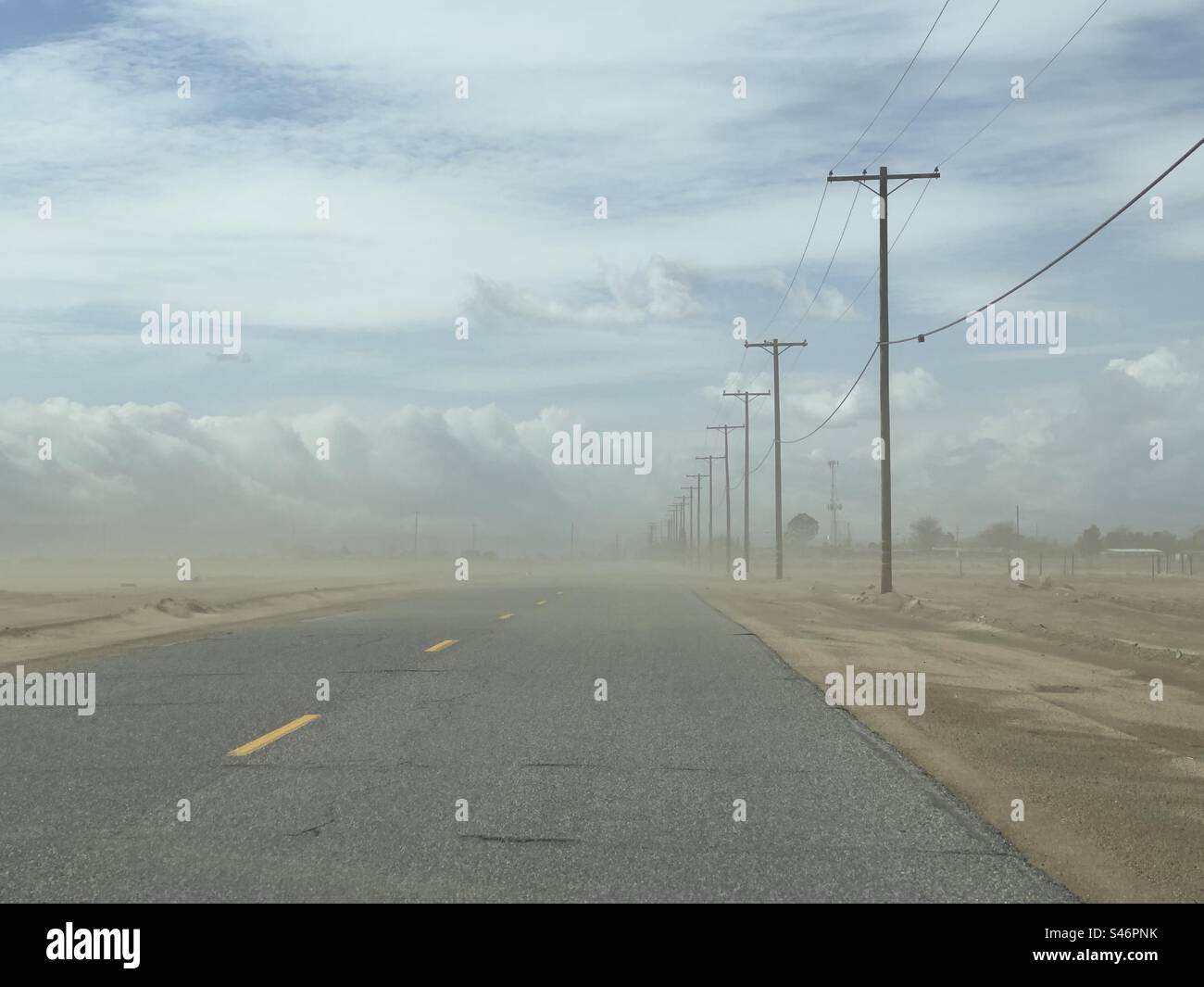 View of road with dust storm on desert highway in southern California, with telegraph poles at side, fading into distance - Smartphone Captured Stock Image