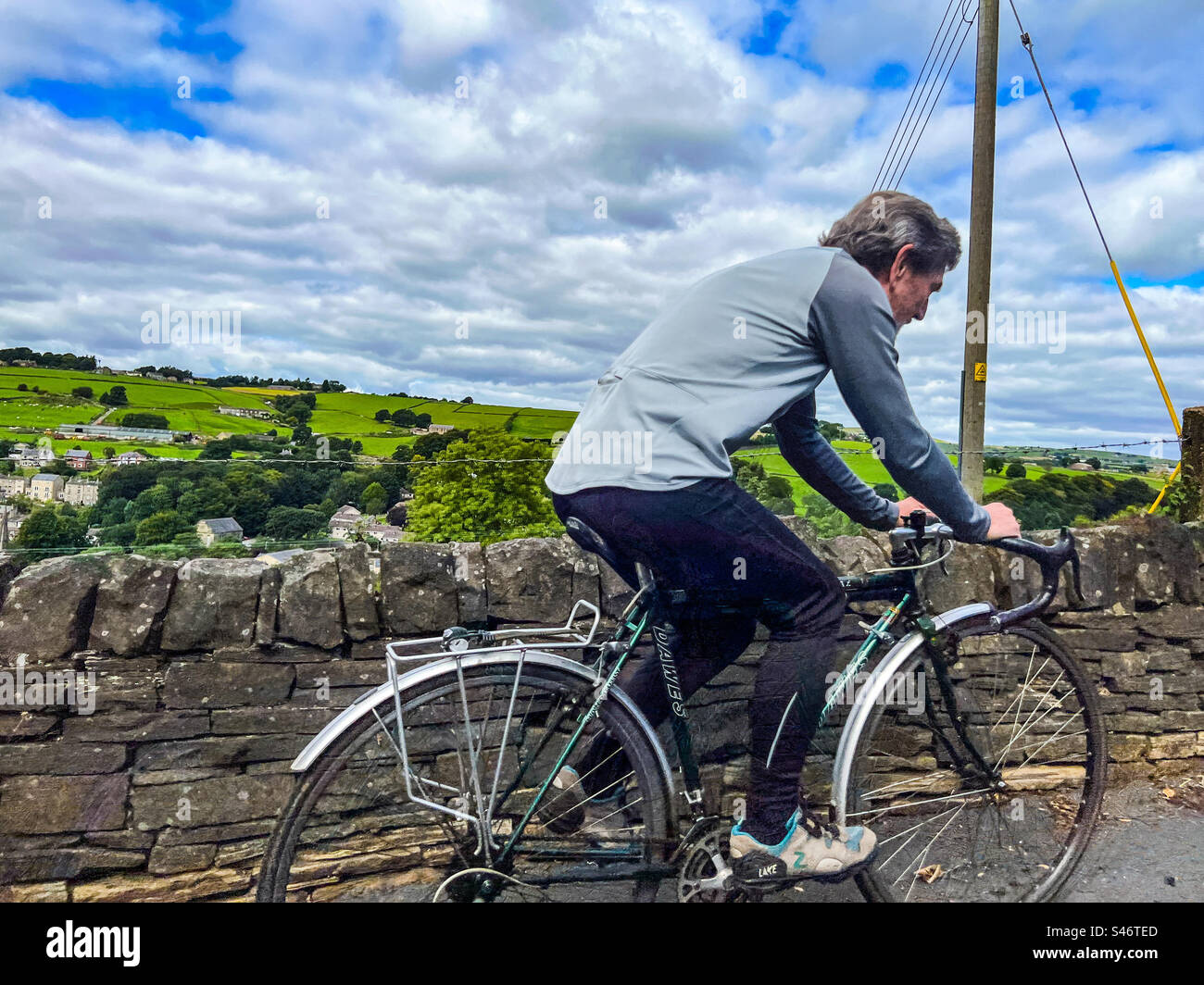 Middle Aged cyclist cycling in the West Yorkshire Pennines village of Ripponden in summer - Smartphone Captured Stock Image