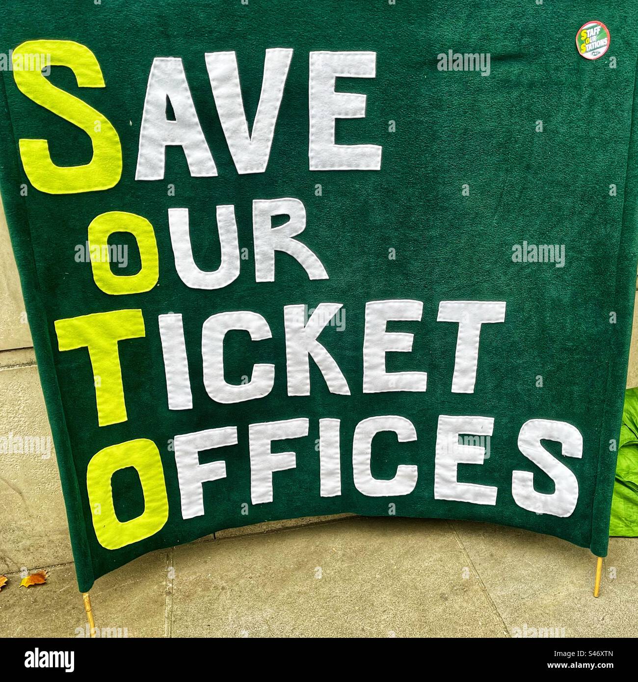 Green Banner says: “Save Our Ticket Offices” as the trade unions in the UK build a coalition to keep staffed ticket offices across the UK railway network - Smartphone Captured Stock Image