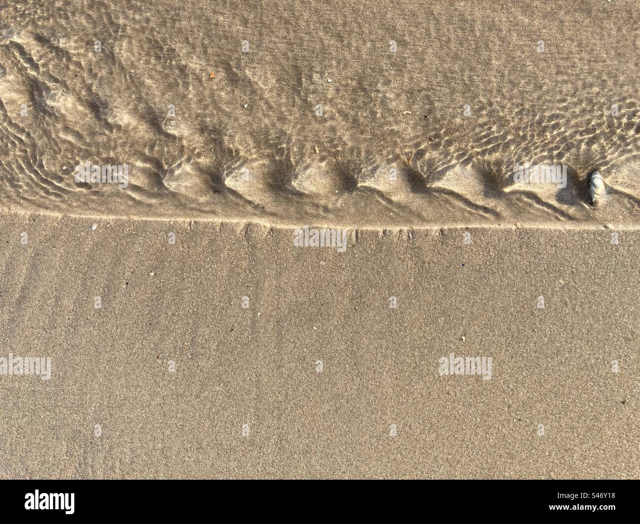 Small water waves of a rivulet on the sand on the beach - Smartphone Captured Stock Image