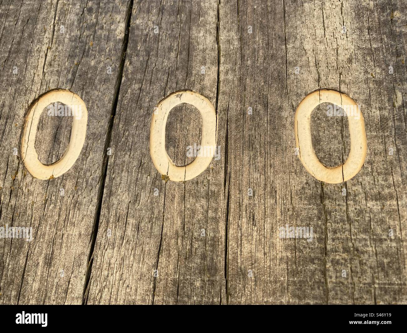 Three white numbers 0 painted on a weathered wooden stake - Smartphone Captured Stock Image