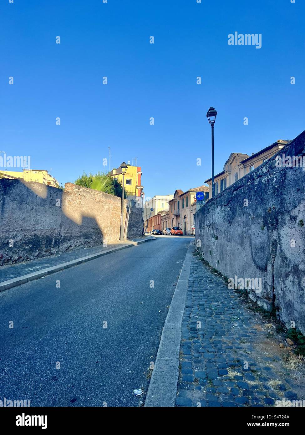 View uphill on Via dei Santi Quattro in the Celio district of Rome. You can find quieter areas in Rome in summer if you wander off the beaten paths. - Smartphone Captured Stock Image