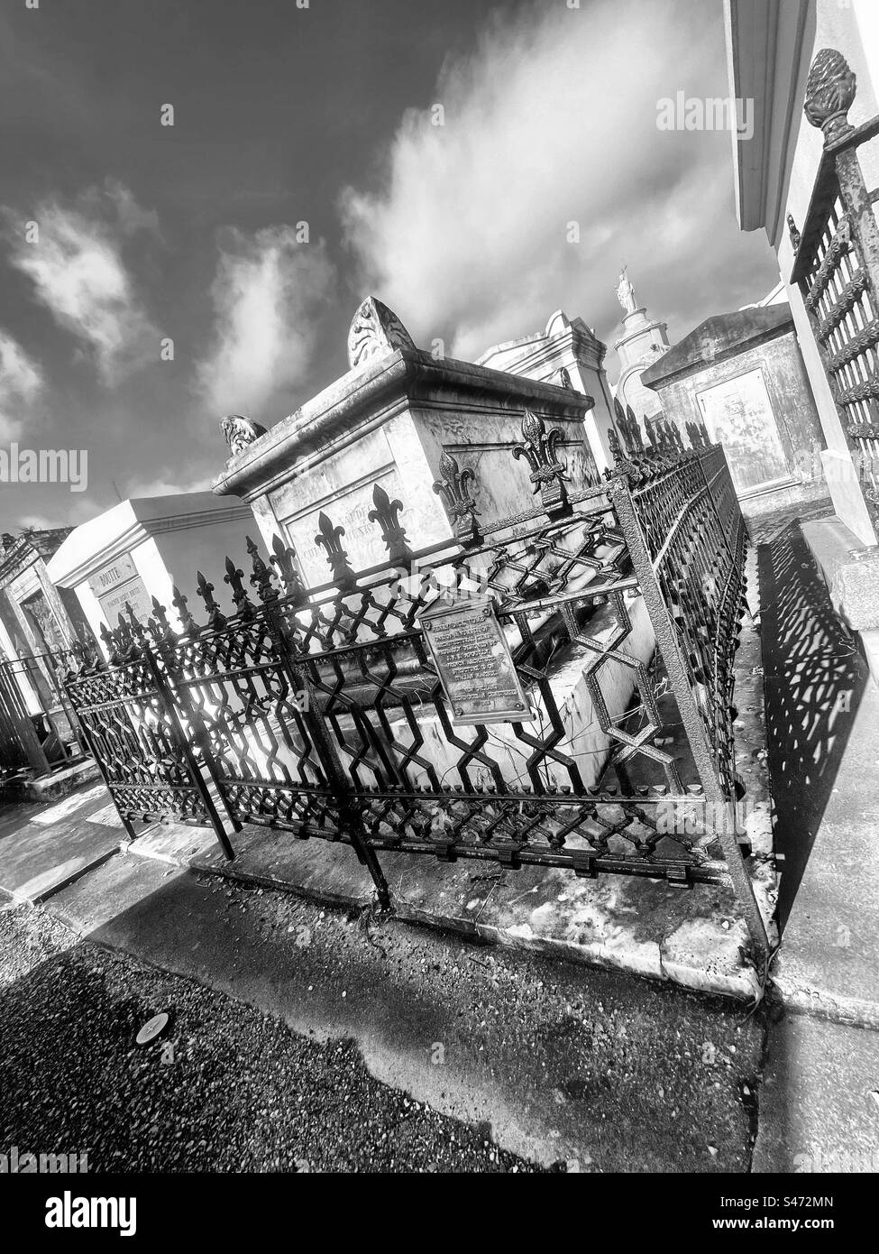Family mausoleums sit behind wrought iron fencing in St. Louis Cemetery No. 1 in New Orleans, Louisiana. Each family owns their mausoleum, and are in charge of maintaining it. - Smartphone Captured Stock Image