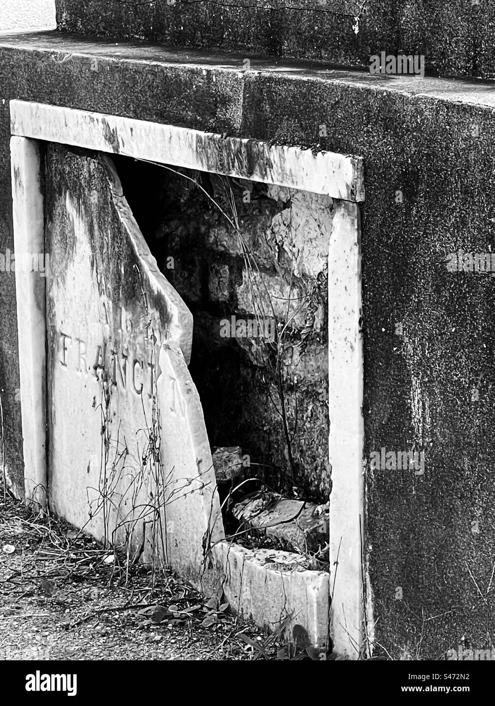 A cracked plaque reveals a brick wall sealing in the occupants of a tomb in St. Louis Cemetery No. 1 in New Orleans, Louisiana. - Smartphone Captured Stock Image