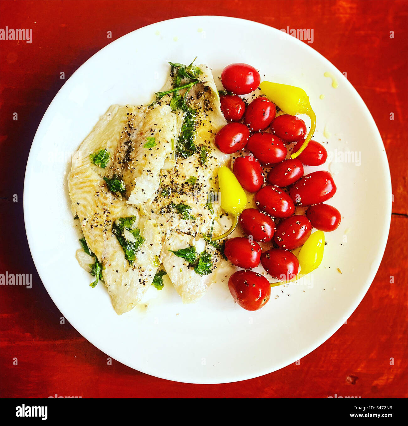 Mero grilled fish, small red tomatoes and yellow hot chilli peppers for lunch in Queretaro, Mexico - Smartphone Captured Stock Image