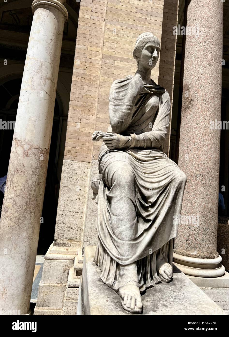 Between columns is a marble statue of a female sitting, Vatican museum - Smartphone Captured Stock Image