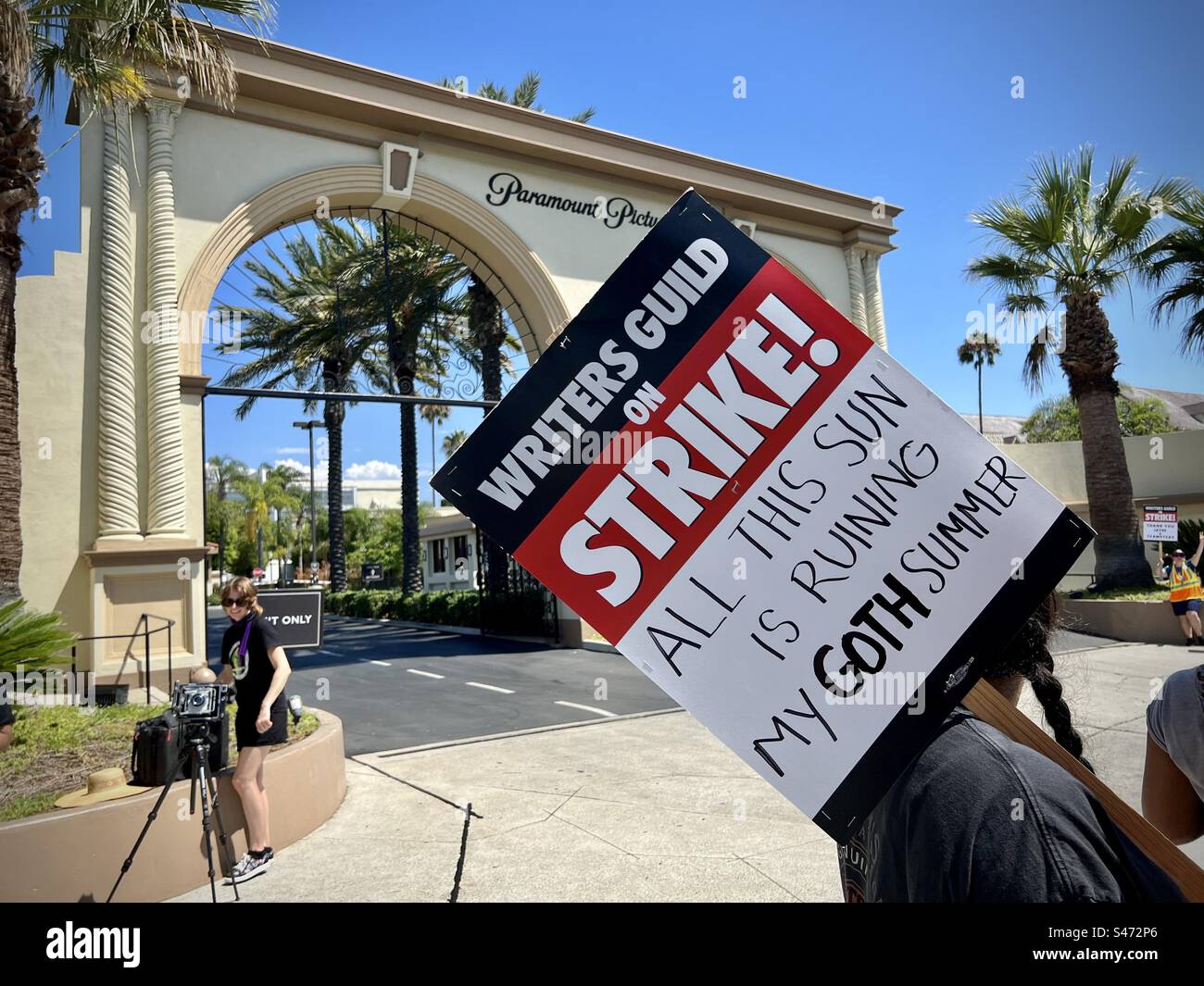 LOS ANGELES, CA, AUG 15, 2023: member of the Writers Guild of America holds 'All this sun is ruining my goth summer' placard, while picketing with other striking writers and actors at Paramount - Smartphone Captured Stock Image