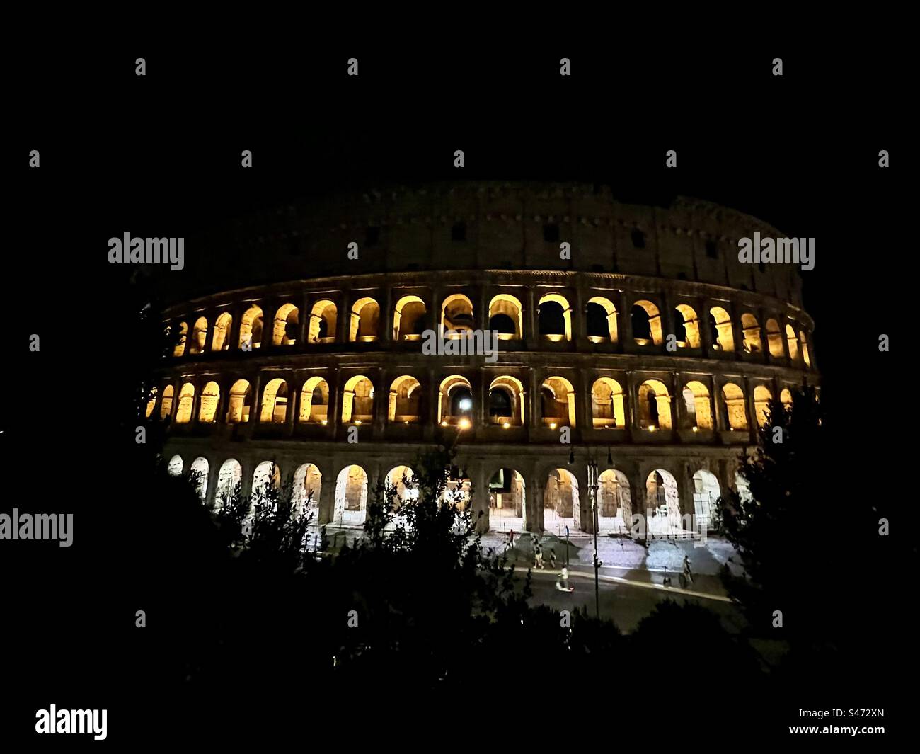 The world famous Roman Colosseum, lit up from the inside but surrounded by the dark of night in Rome. - Smartphone Captured Stock Image