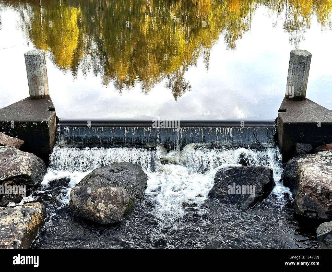 Small dam with water flowing over it - Smartphone Captured Stock Image