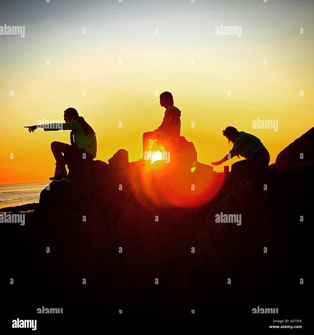 3 silhouettes baclklight on the sunset near the sea - Smartphone Captured Stock Image