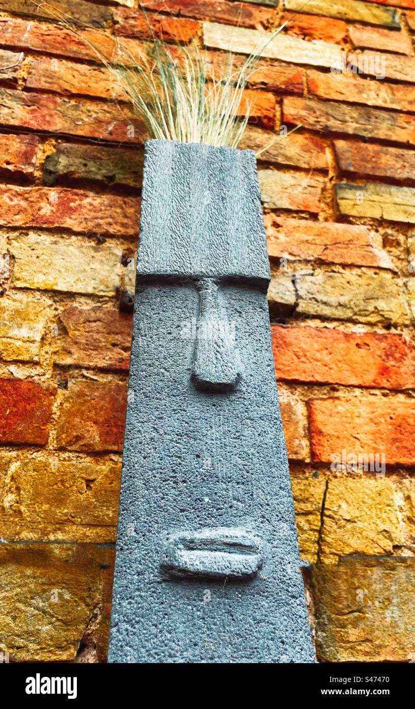 Easter Island man pot with grass for hair against a brick wall Stock Photo