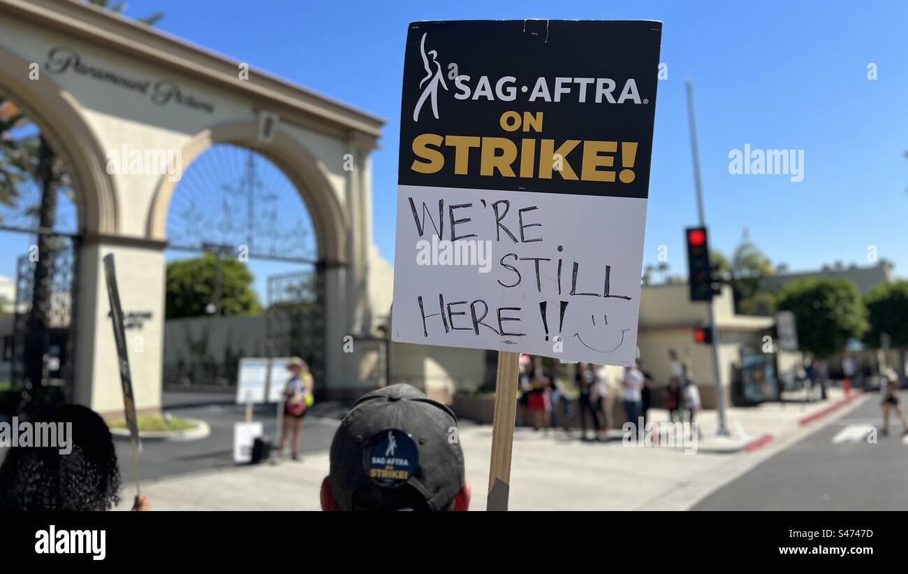 LOS ANGELES, CA, JUN 30, 2023: striking actor holding SAG-AFTRA sign saying "We're still here" while picketing outside Paramount Pictures in Hollywood Stock Photo