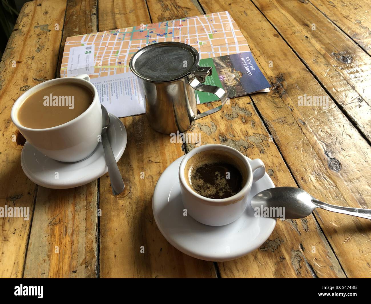 A cup of espresso, a cup of coffee and a map with writing in Spanish on the rustic wooden table, Mexico City, 2022 - Smartphone Captured Stock Image