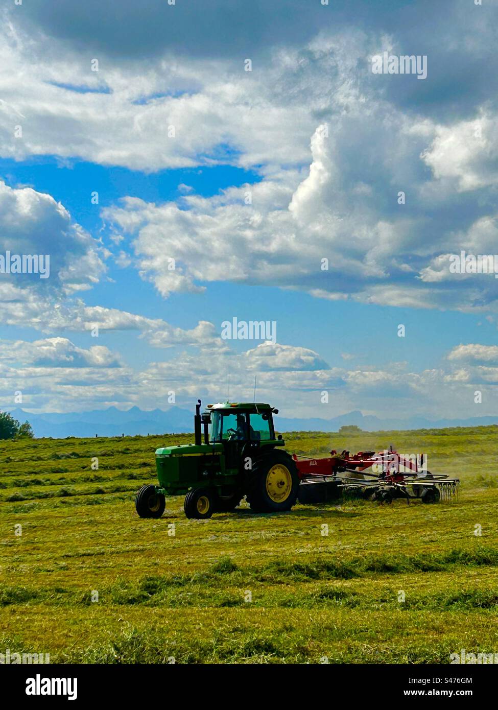 Raking the the hay in southern Alberta, Canada, agriculture, crop, farming, modern machinery, sunny day, making hay while the sun shines - Smartphone Captured Stock Image
